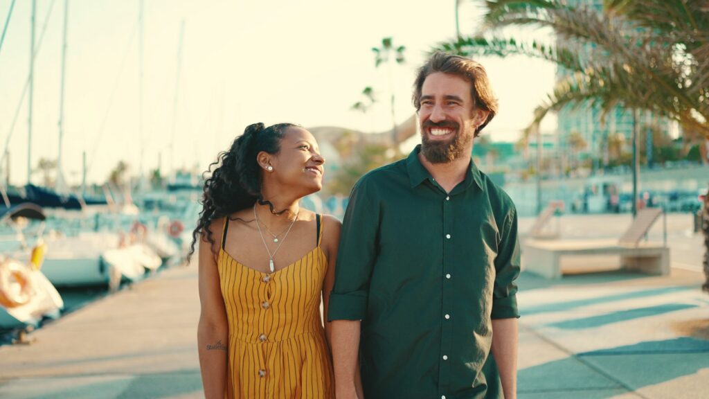 Close-up of young happy man and woman walking along the promenade holding hands and joyfully