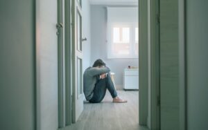 Man with mental disorder crying sitting on room floor