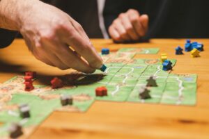 men friends have fun playing the carcassonne board game at night. male hands and game cards and chip